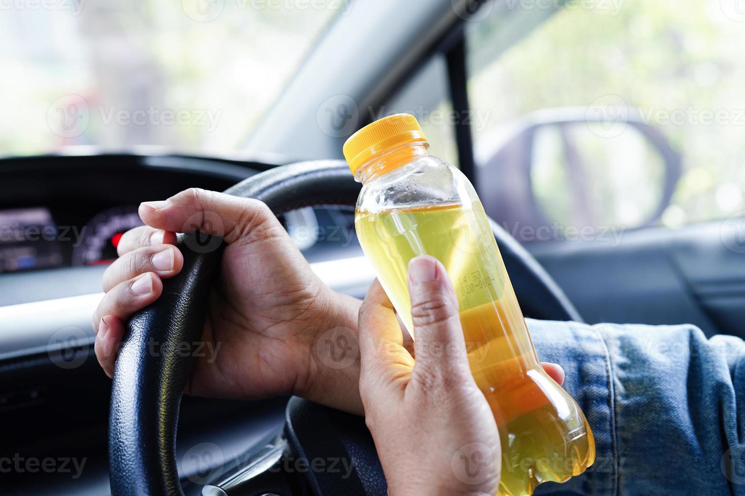 asiatisk kvinna förare håll kall vatten för dryck i bil, farlig och risk ett olycka. foto