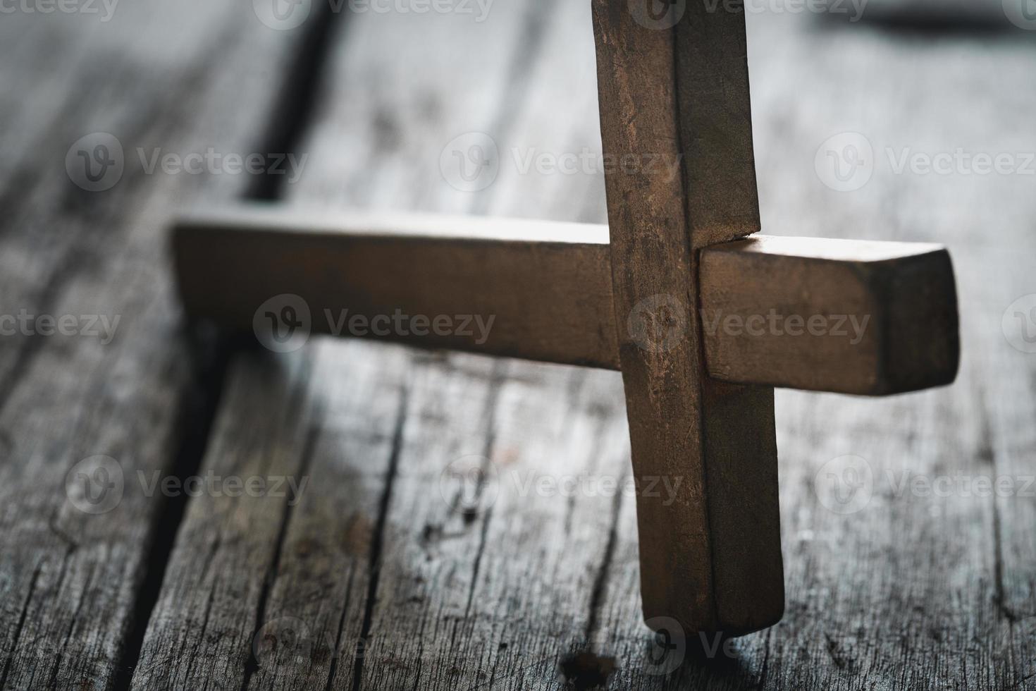 en trä- kristen korsa krucifix på en grunge styrelse bakgrund. trä- kristen korsa på grå tabell mot suddig lampor, Plats för text. foto
