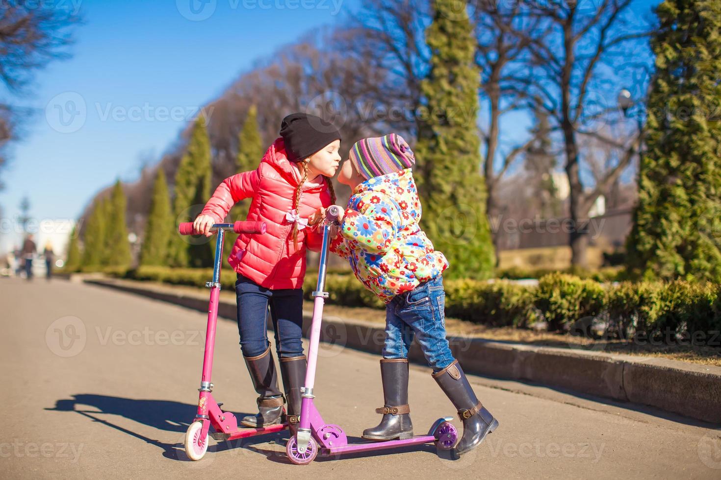 liten systrar ridning skotrar utomhus foto