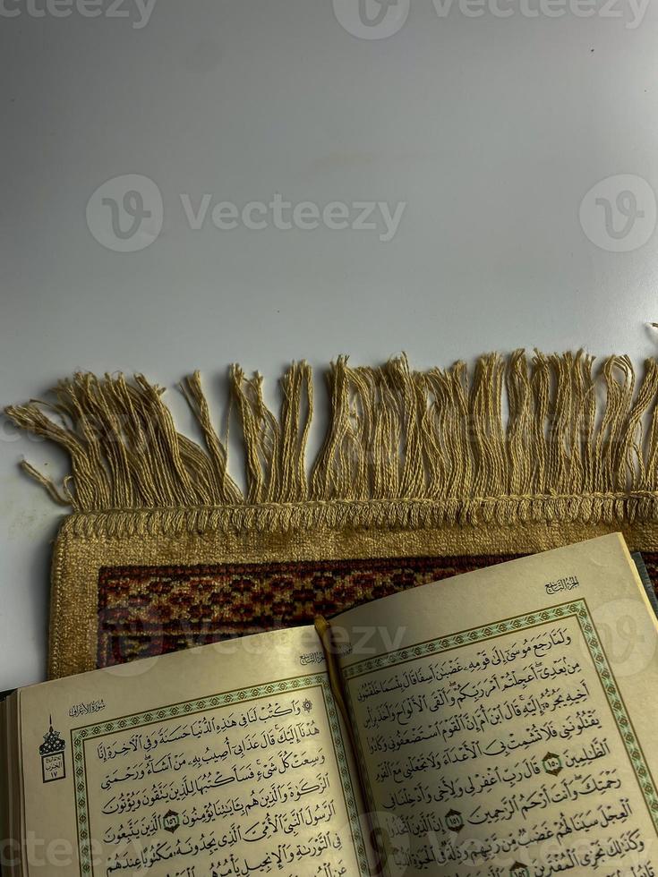 läsning al quran och vändning sida av quran ovan sajadah bön- matta isolerat på vit Plats. vald fokus foto