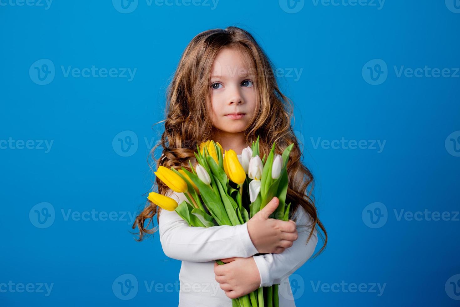 porträtt av en charmig leende liten flicka med en bukett av tulpaner i henne händer. livsstil. färsk blommor. internationell kvinnors dag. Plats för text. hög kvalitet Foto