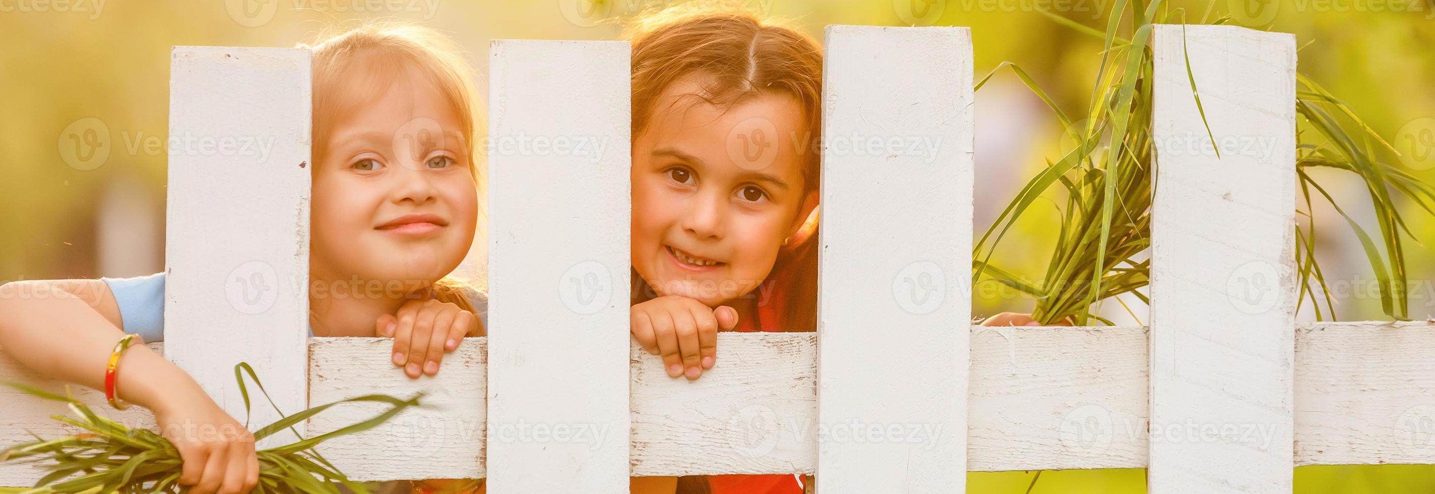 två skön ung flickor i de trädgård staket foto