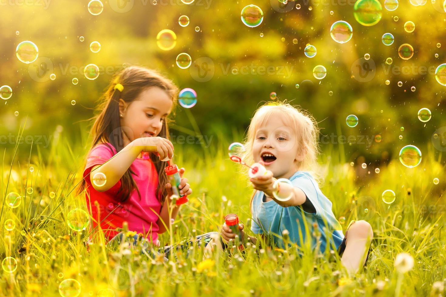 liten flickor blåser tvål bubblor med henne mormor utomhus foto