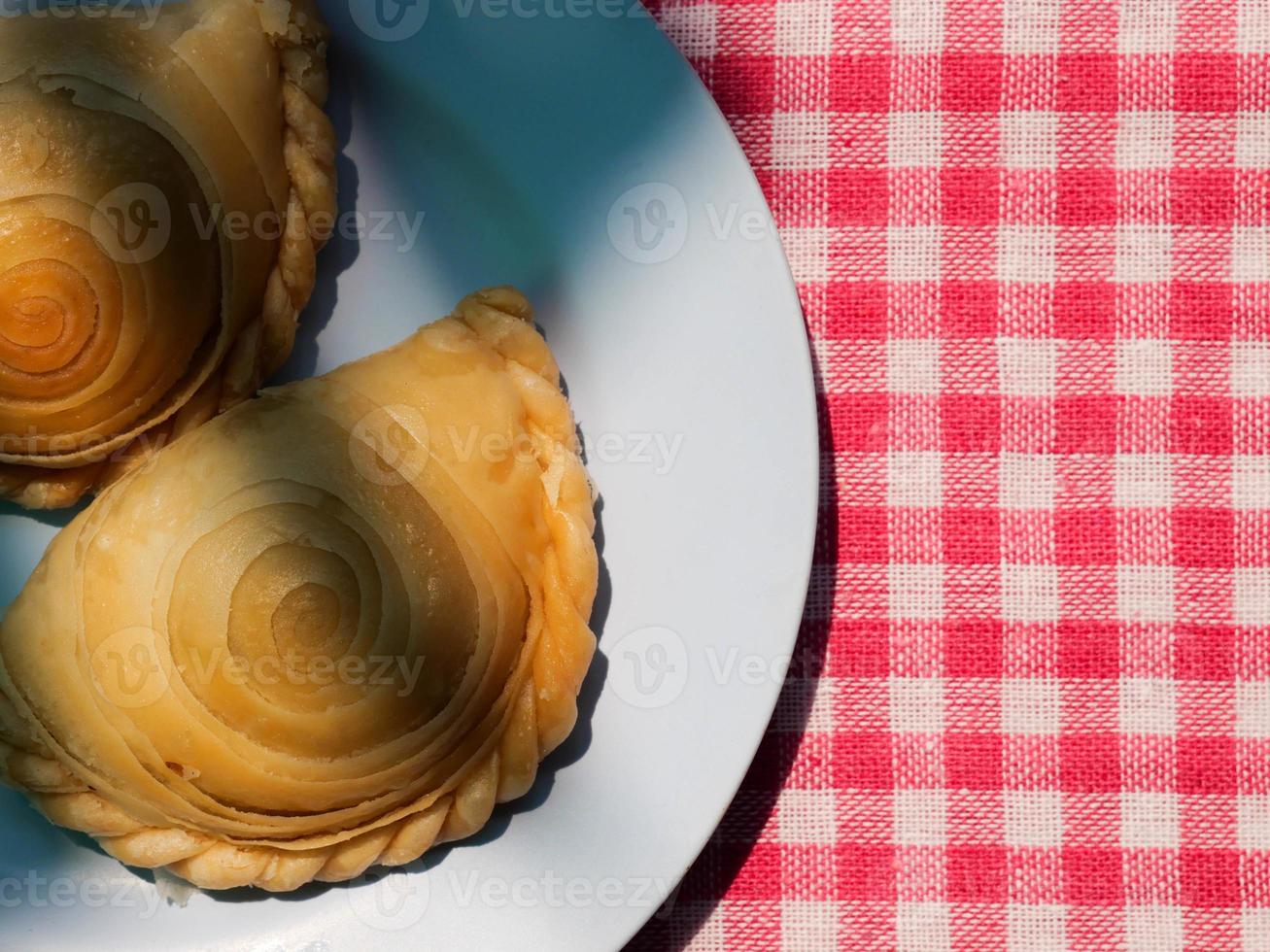 curry puffar på tallrik stänga upp med röd pläd tyg som bakgrund foto