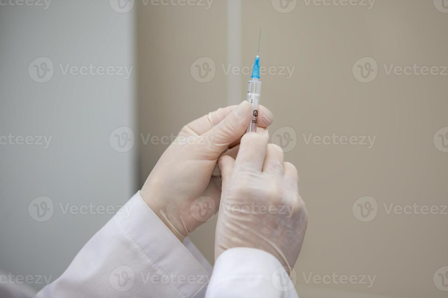 läkares händer i sudd handskar håll en spruta med medicin. foto