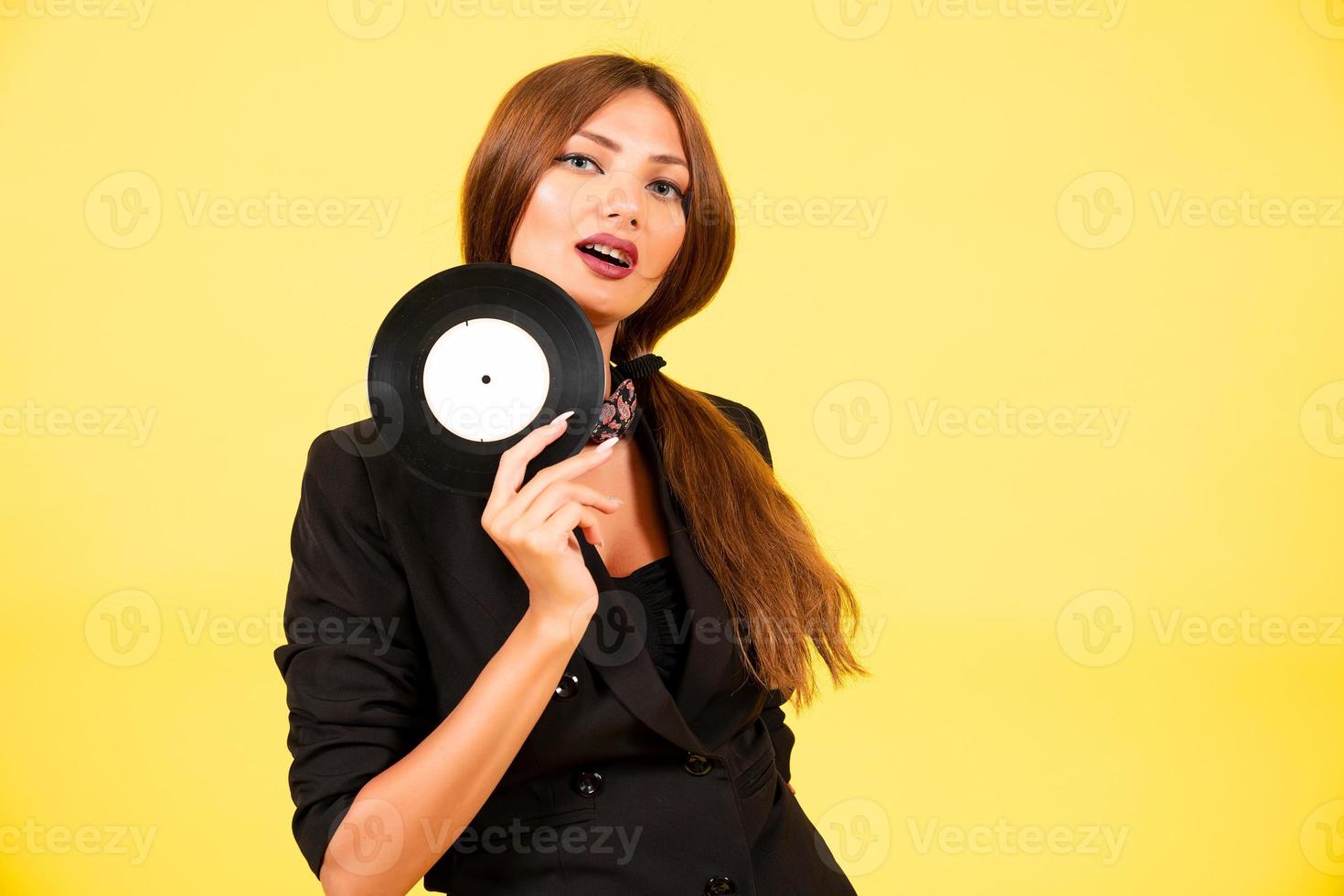 flicka i en svart kostym på en gul bakgrund med en spela in i henne händer, musik, de flicka visar känslor foto
