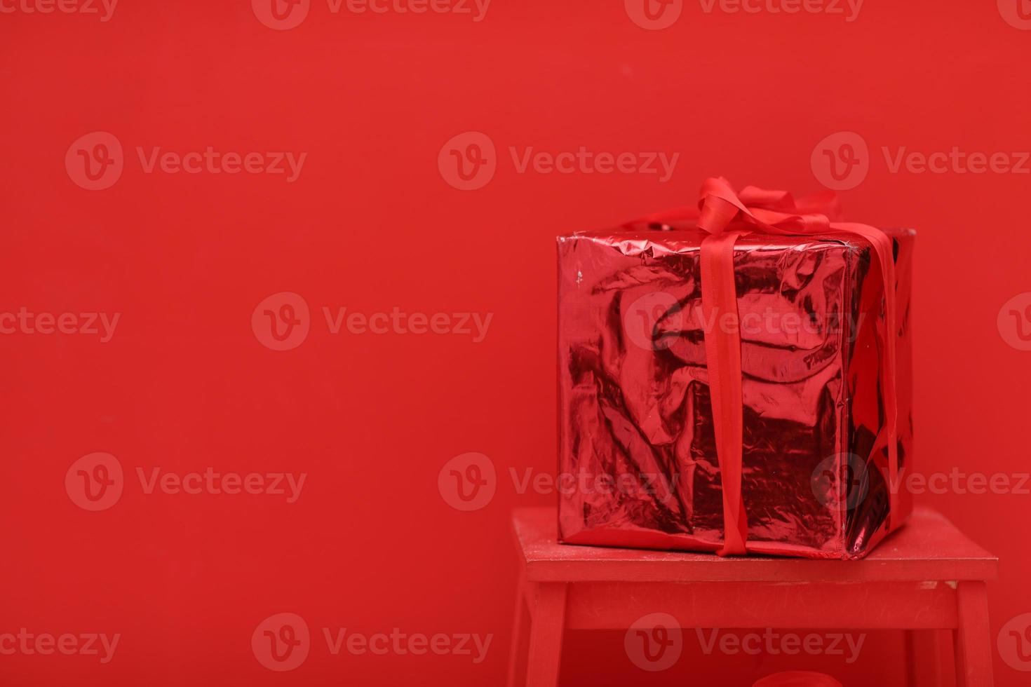 närvarande för valentines dag. röd skinande gåva låda med röd band på röd bakgrund. överraskning för kärlek människor. födelsedag, jul, ny år. plats för text, kopia Plats foto