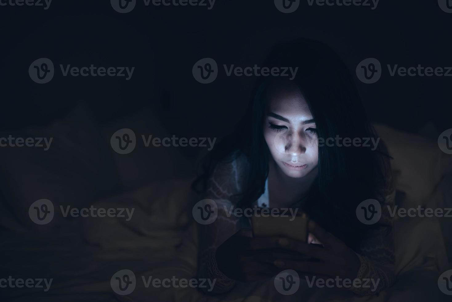 asiatisk kvinna spelar spel på smartphone i de säng på natt, thailand människor, missbrukare social media foto