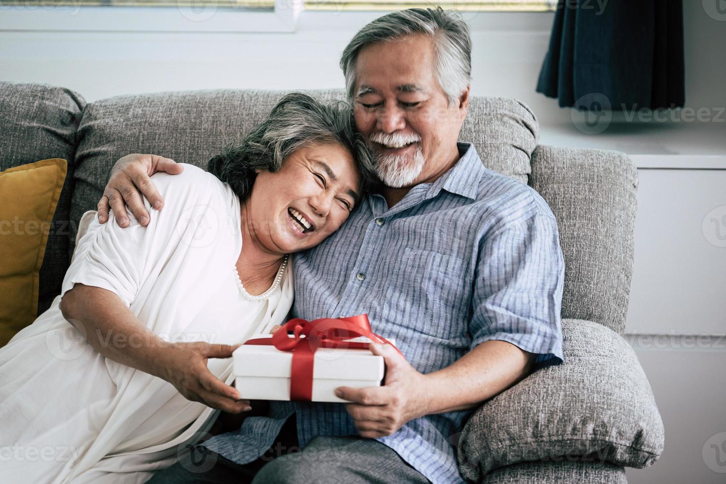 äldre par överraskar med presentask i vardagsrummet foto