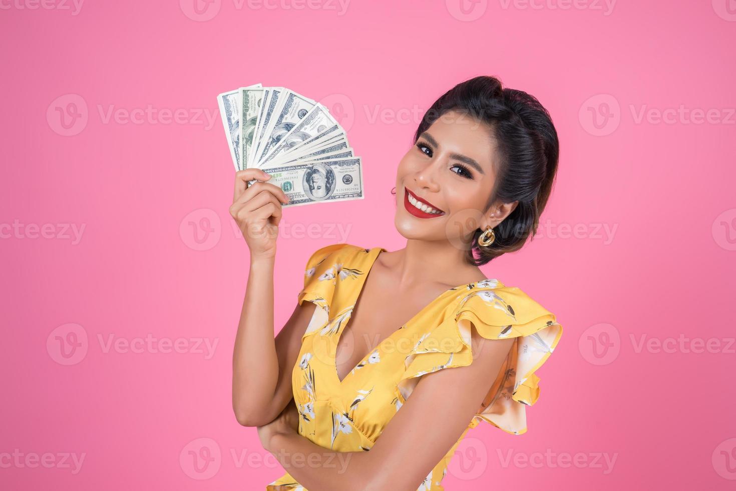glad moderiktig kvinna som håller pengar för shopping foto