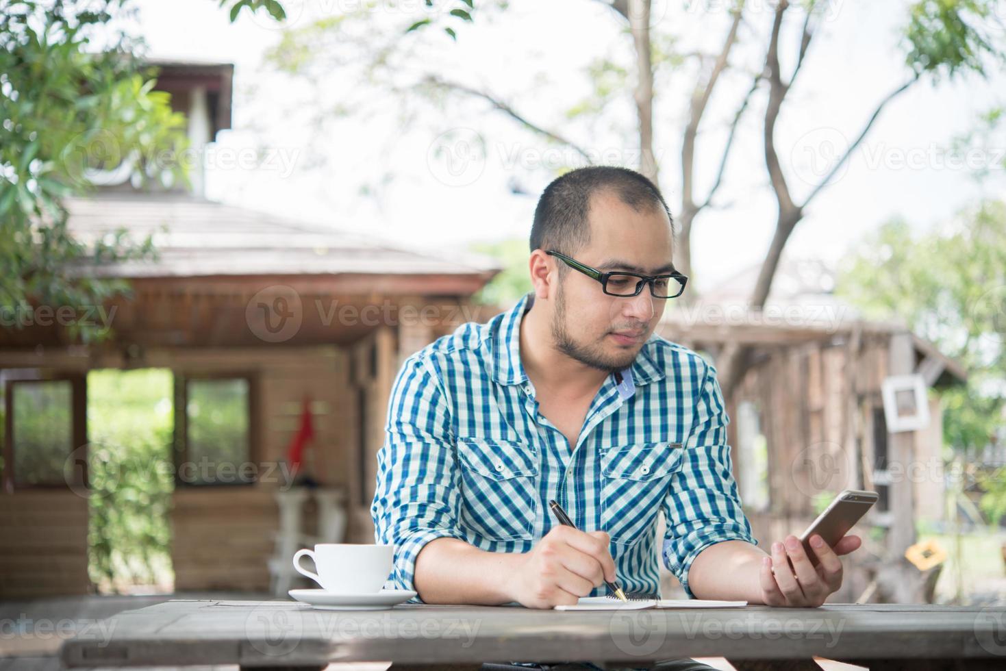 ung affärsman som använder smartphonen medan han arbetar i hemträdgården foto