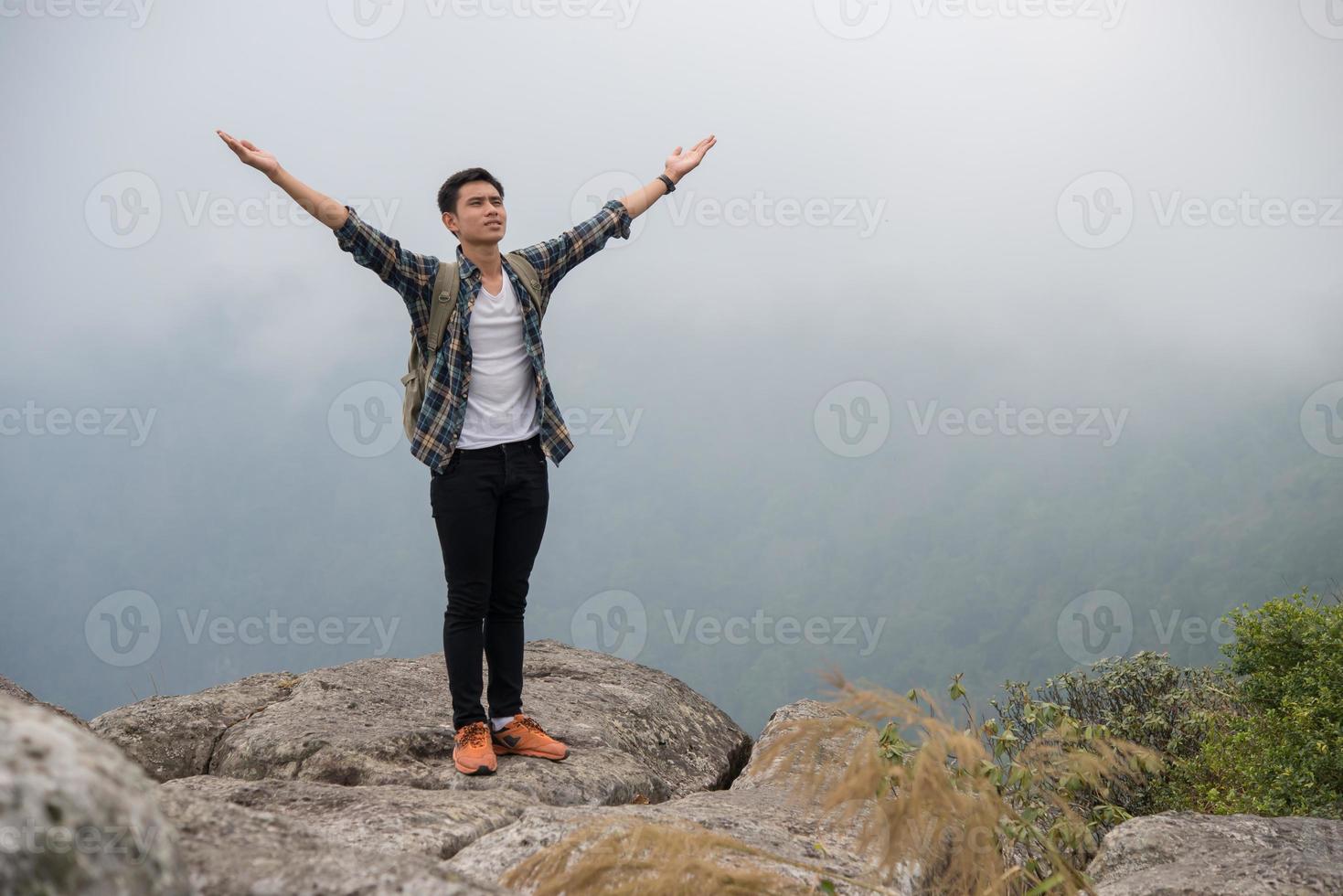 vandrare med ryggsäck som står på toppen av ett berg med upphöjda händer foto