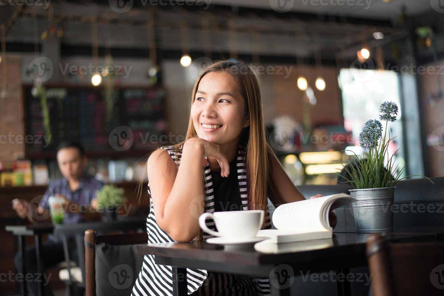 asiatisk kvinna som kopplar av och läser en bok på kaféet foto