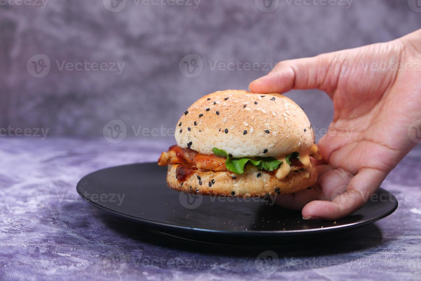 hand som håller en nötköttburger på ett bord på nära håll foto