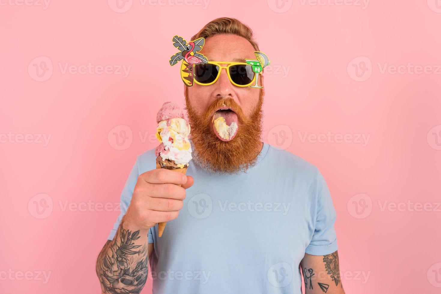 hungrig man med skägg och tatueringar äter en stor glass foto
