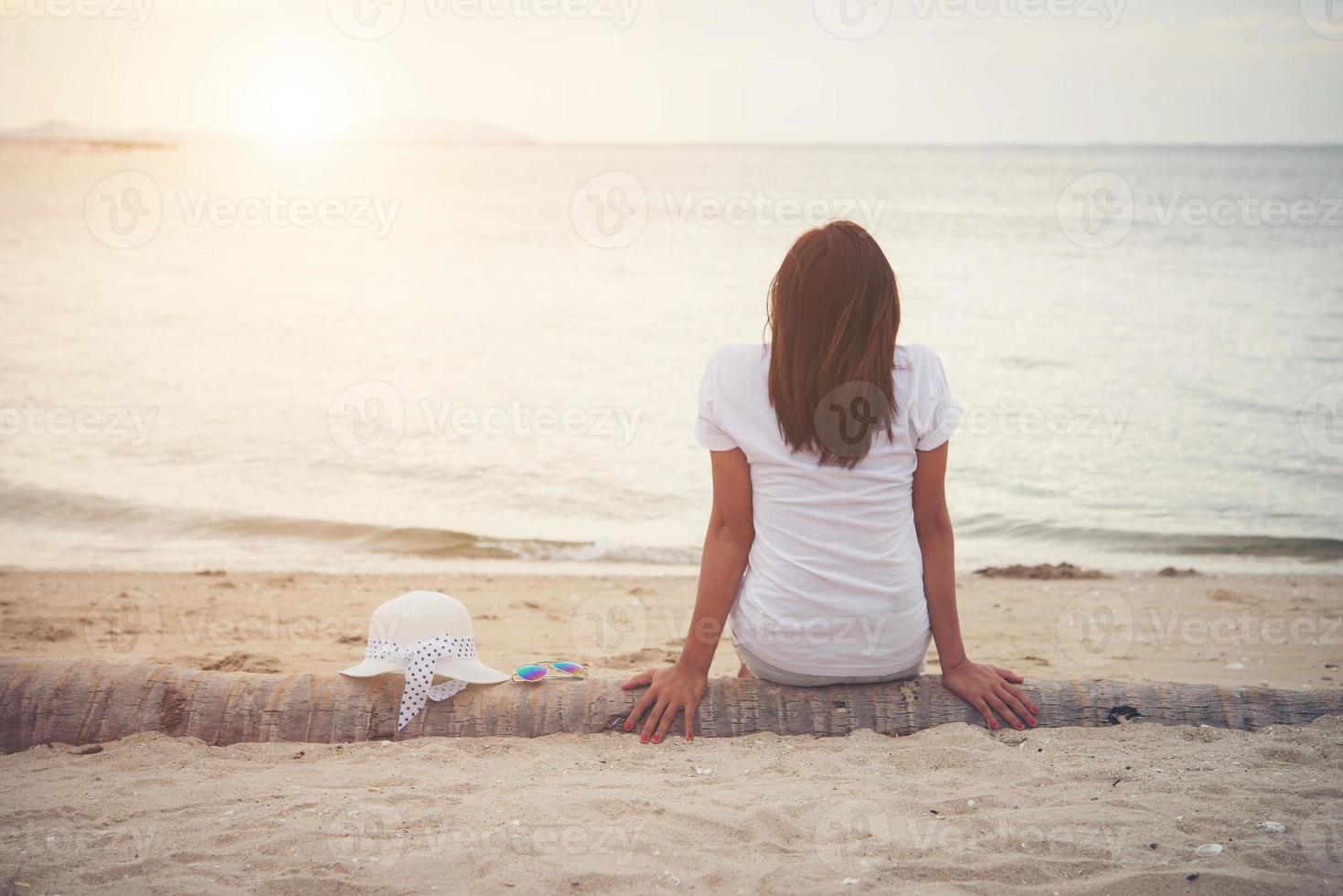 baksida av ung kvinna som sitter på stranden foto