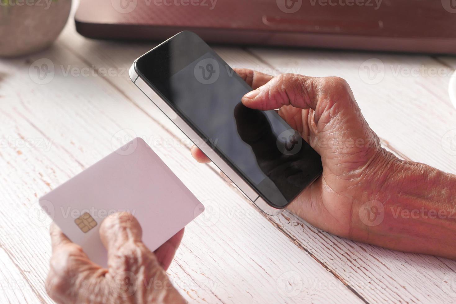 seniors händer som håller en mobiltelefon foto