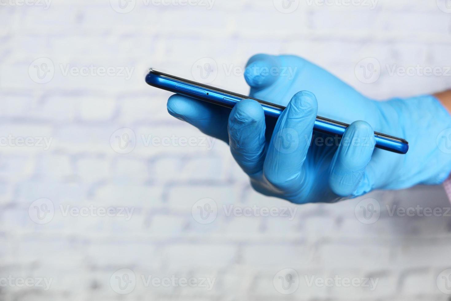 hand som bär handskar som tittar på smart telefon foto