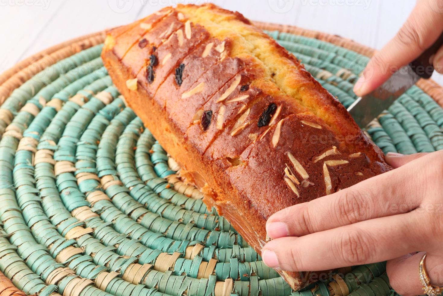 kvinnas hand som skär en tårta på bordet foto