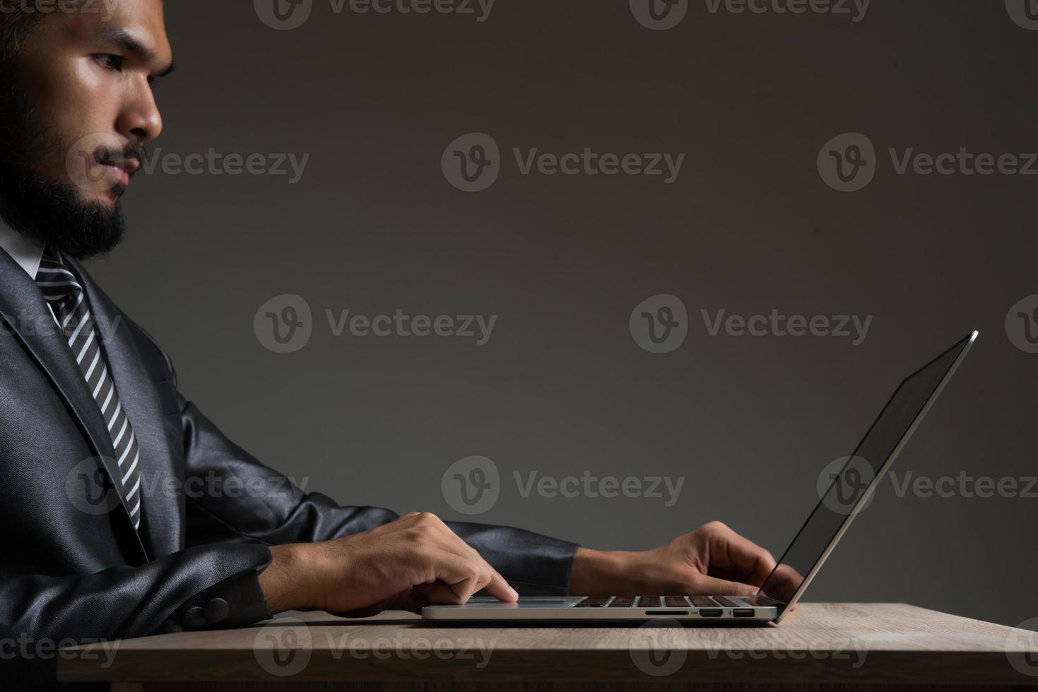 ung affärsmansammanträde som arbetar med bärbara datorn som isoleras på svart bakgrund foto