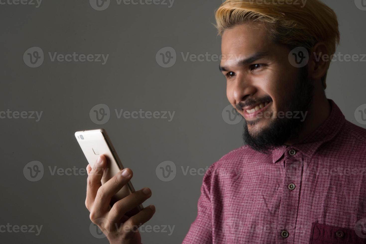 stilig hipster man ler medan du använder smartphone isolerad på svart bakgrund foto