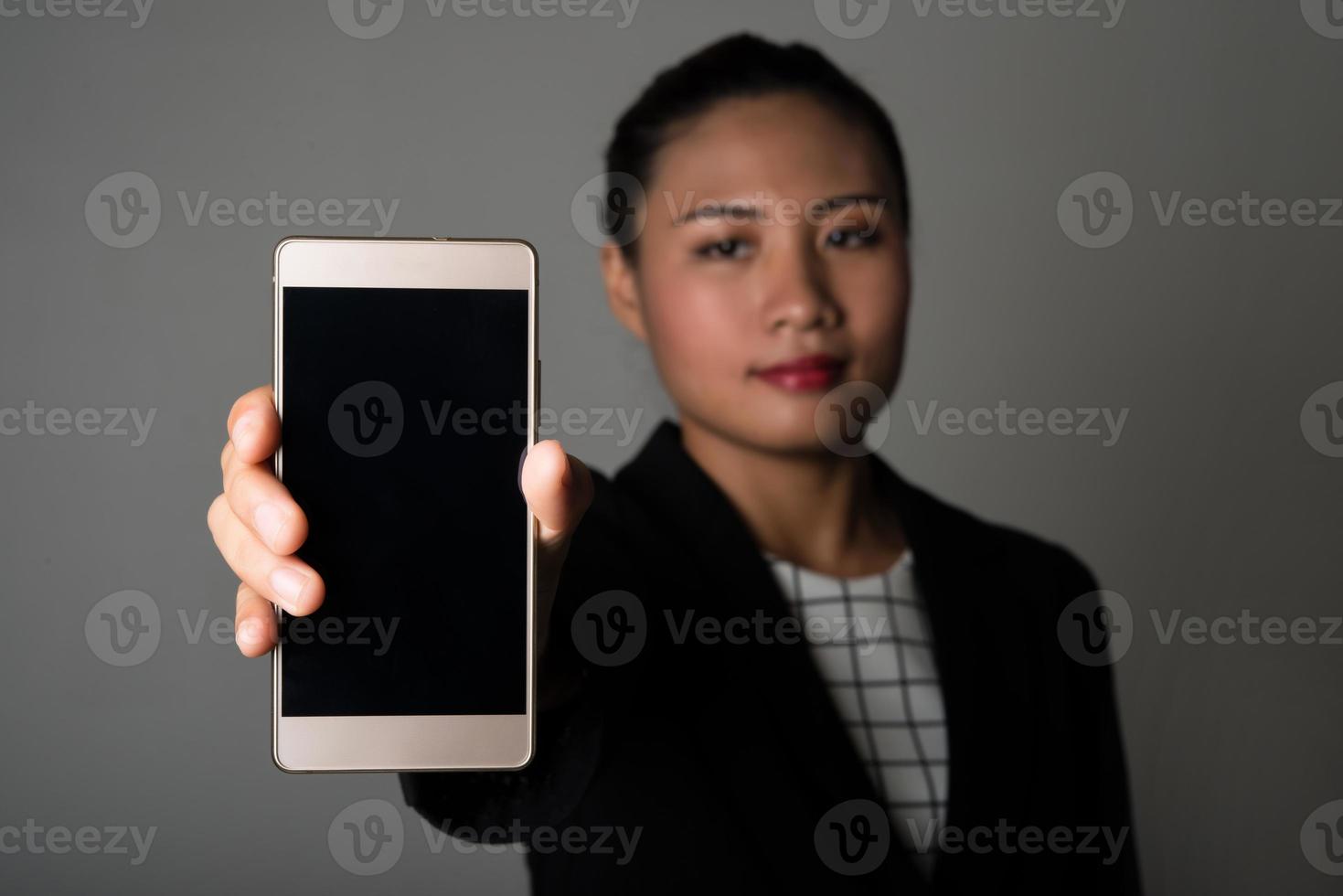 porträtt av affärskvinnan visar smarttelefonen mot svart bakgrund foto