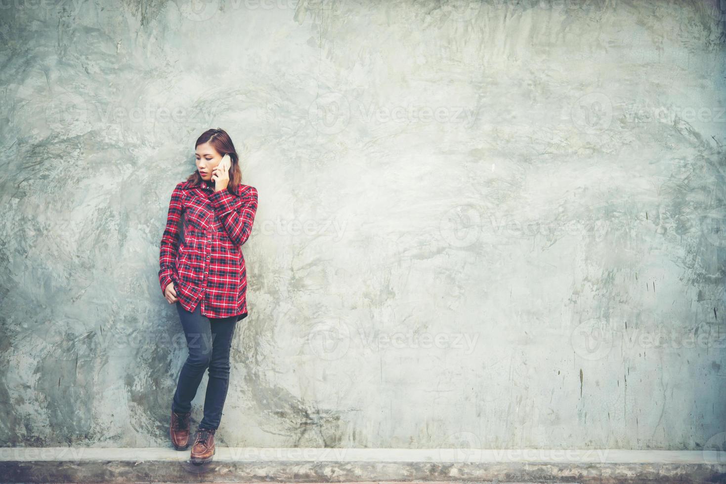 vacker ung hipster stående talar på smartphone isolerad med grunge bakgrund foto