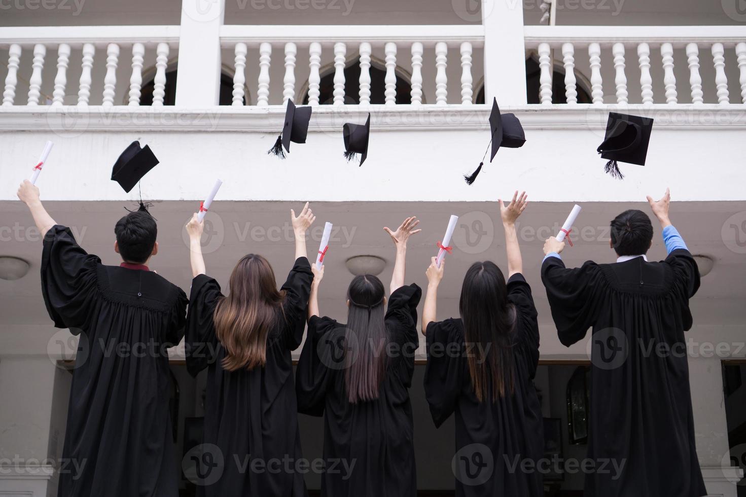 grupp framgångsrika studenter som slänger examenhattar i luften och firar foto