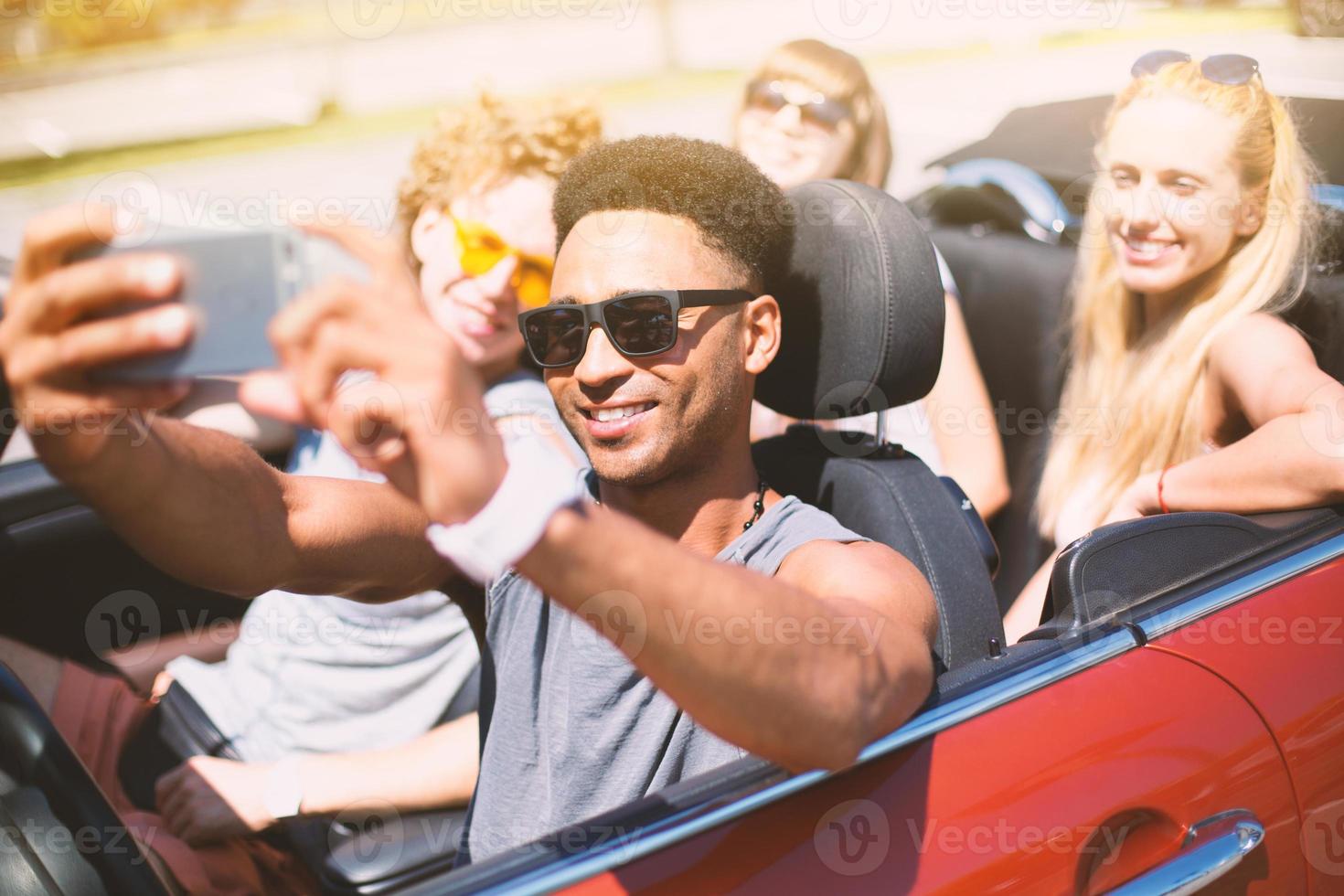 ung vänner ta en selfie i en cabriolet bil foto