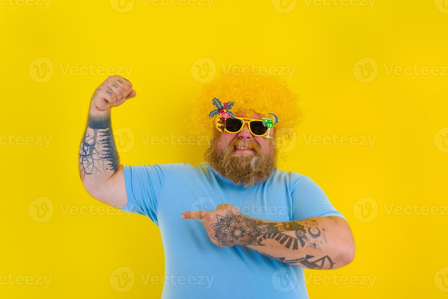 fett man med peruk i huvud och solglasögon visar hans muskel foto