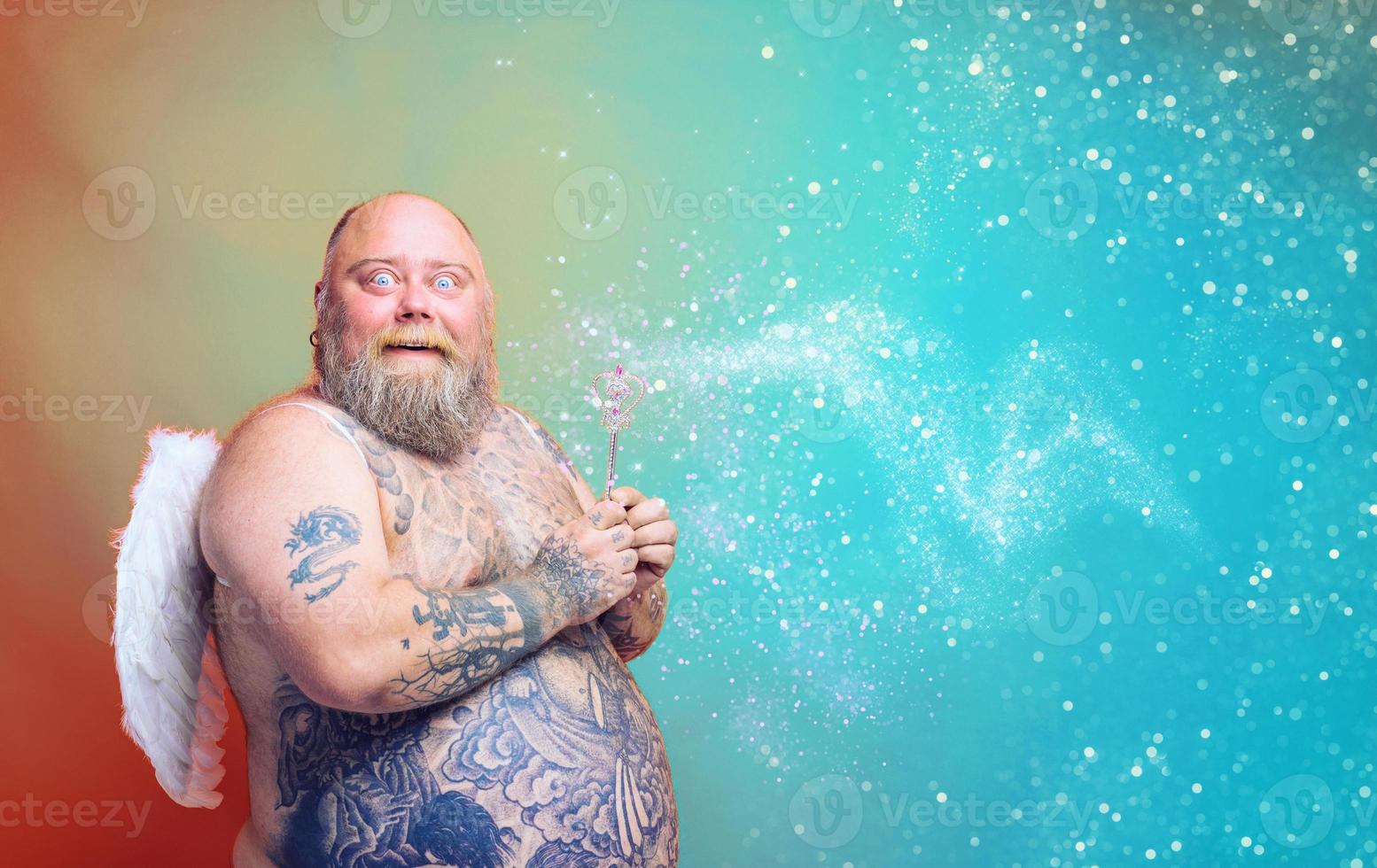 fett förvånad man med skägg , tatueringar och vingar handlingar tycka om ett magi fe- foto