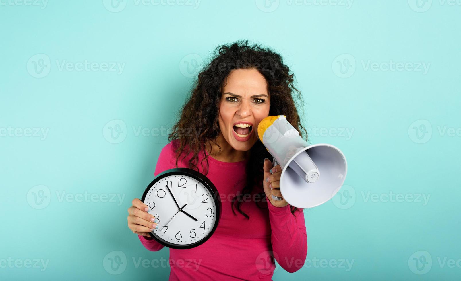 kvinna skriker med högtalare eftersom är för sent. arg uttryck. cyan bakgrund foto