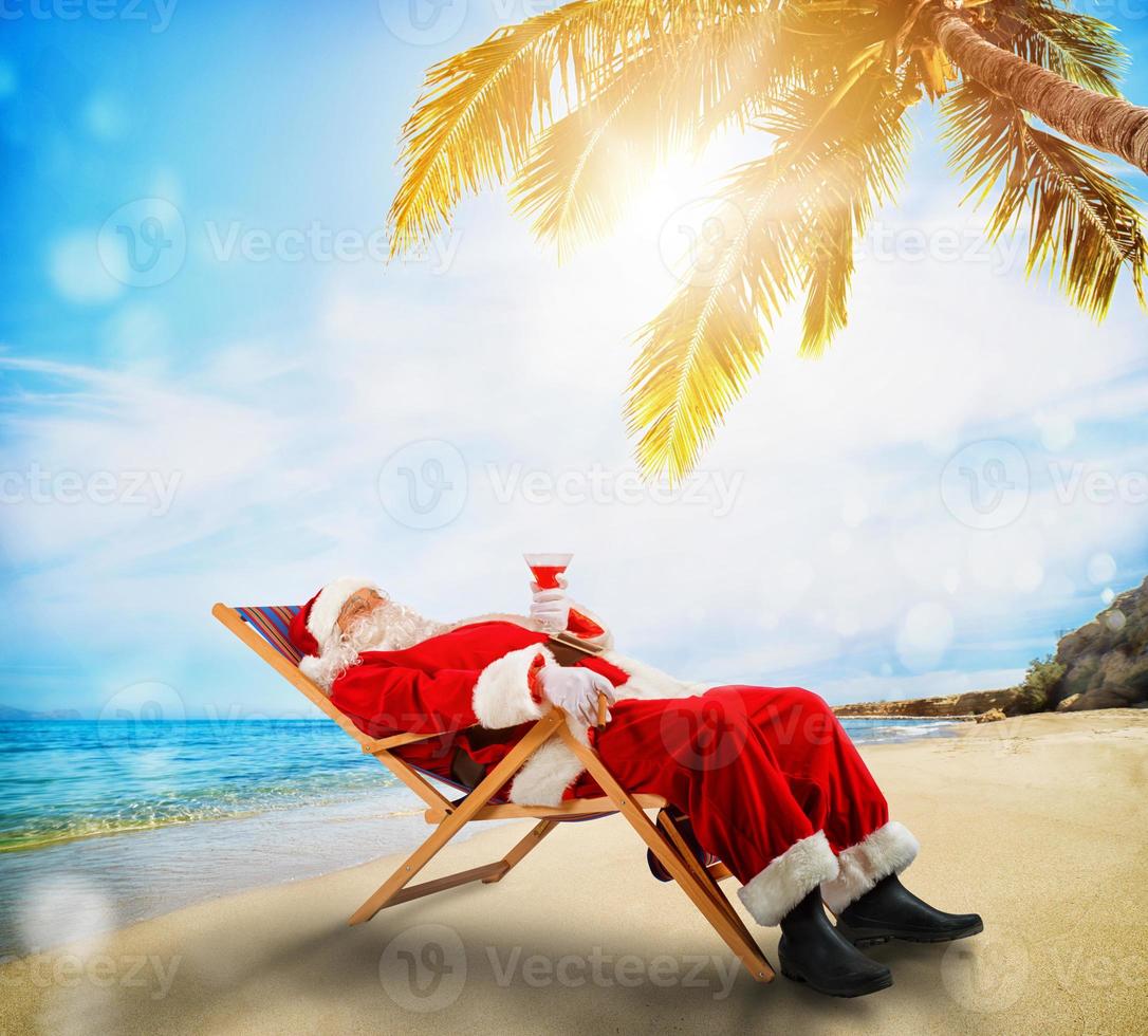 santa claus avkopplande på en deckchair i en tropisk strand foto