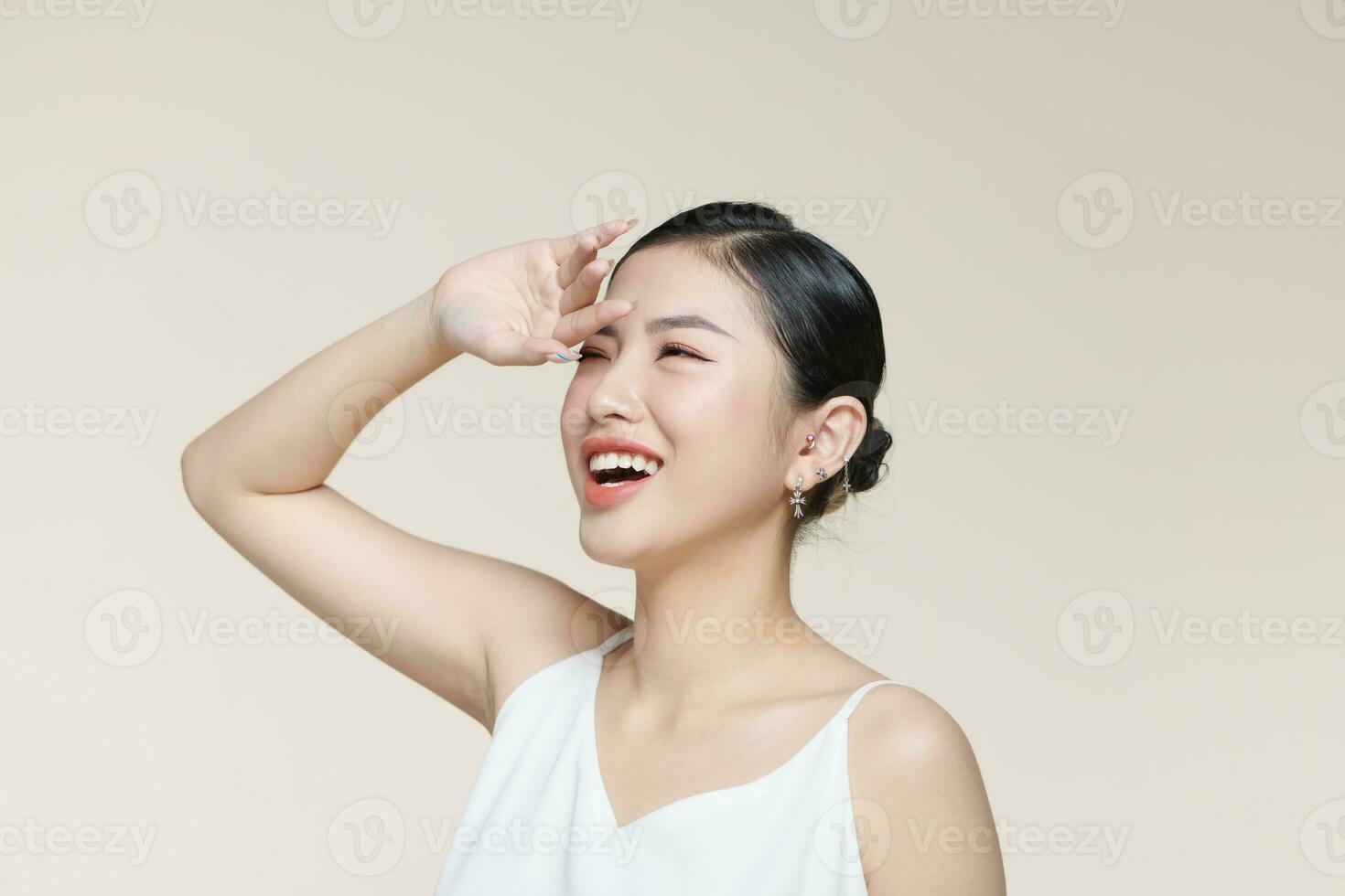 ung asiatisk kvinna omslag henne ansikte från de Sol med handflatan mot en beige bakgrund foto