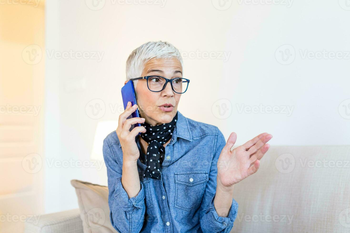 skön caucasian äldre kvinna har telefon konversation med henne gammal vän använder sig av elektronisk enhet, diskuterar senast Nyheter med söt leende på henne ansikte, Sammanträde på Hem foto