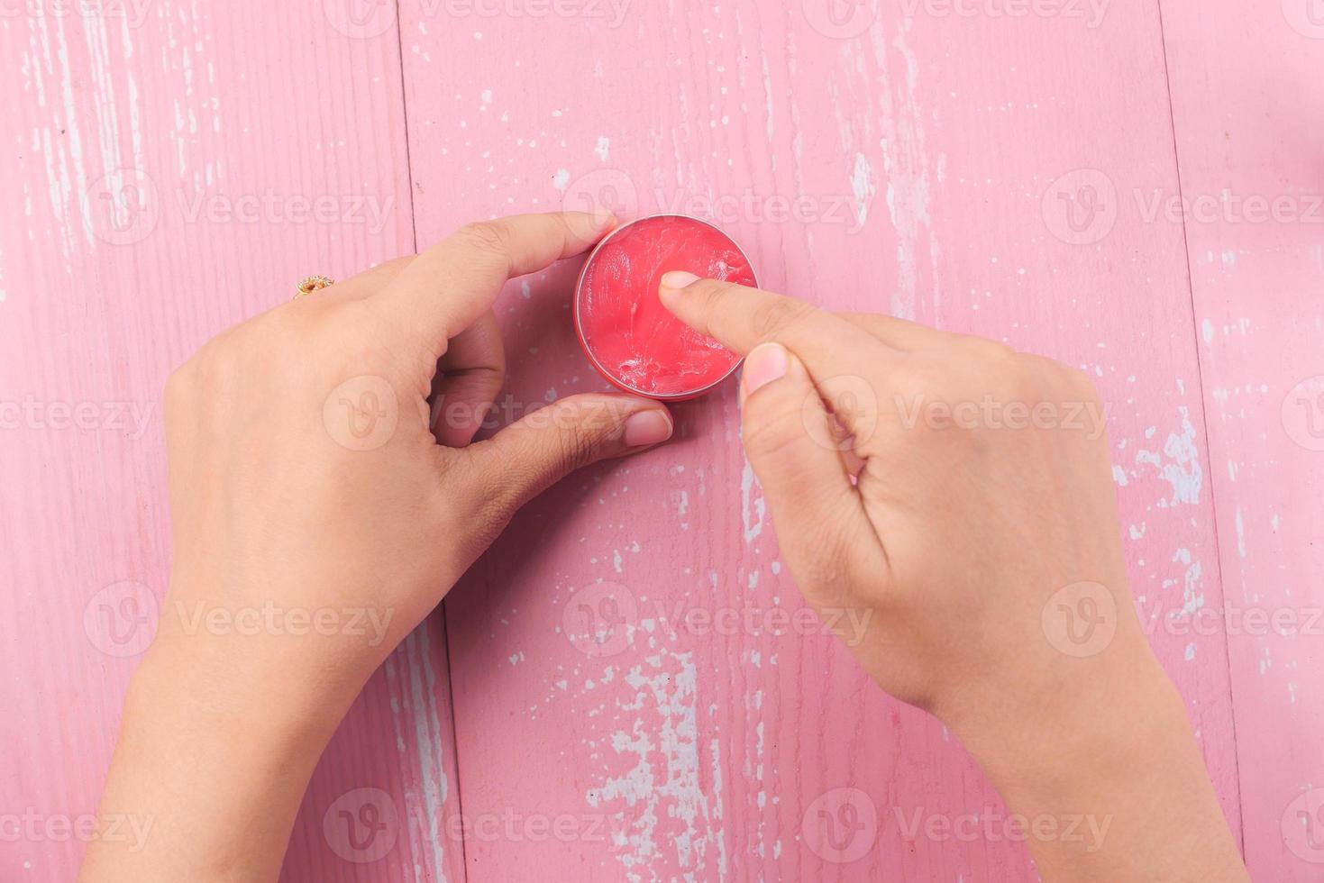kvinna som använder vaselin på rosa bakgrund foto