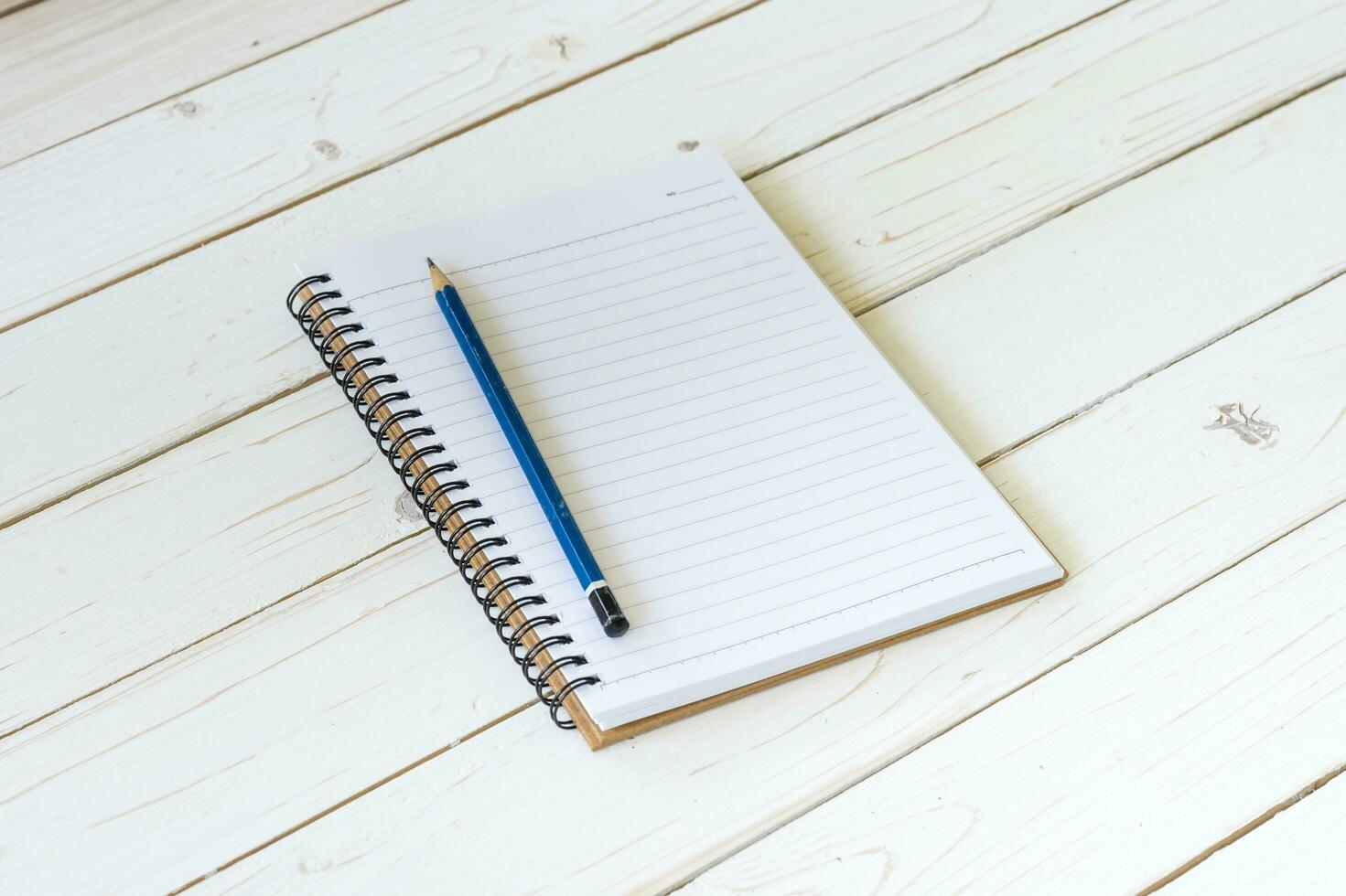 öppen anteckningsbok med tom sidor och penna på trä tabell foto