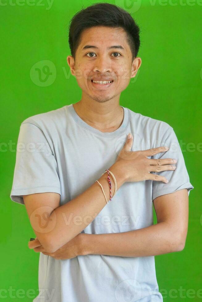 uttrycksfull tillfällig balinesisk asiatisk kille modell för reklam med grön skärm studio bakgrund foto