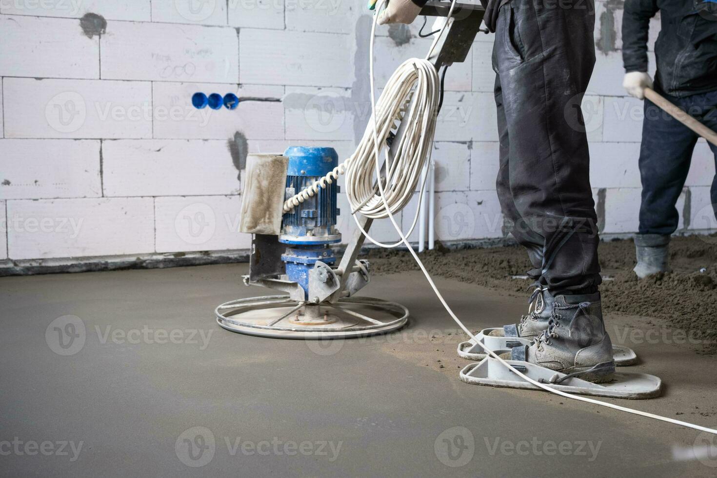 ramma och slipning av halvtorr golv golv förbi en maskin med en roterande disk för utjämning. konstruktion av en betong golv i de hus, en bemästra med särskild Utrustning. foto
