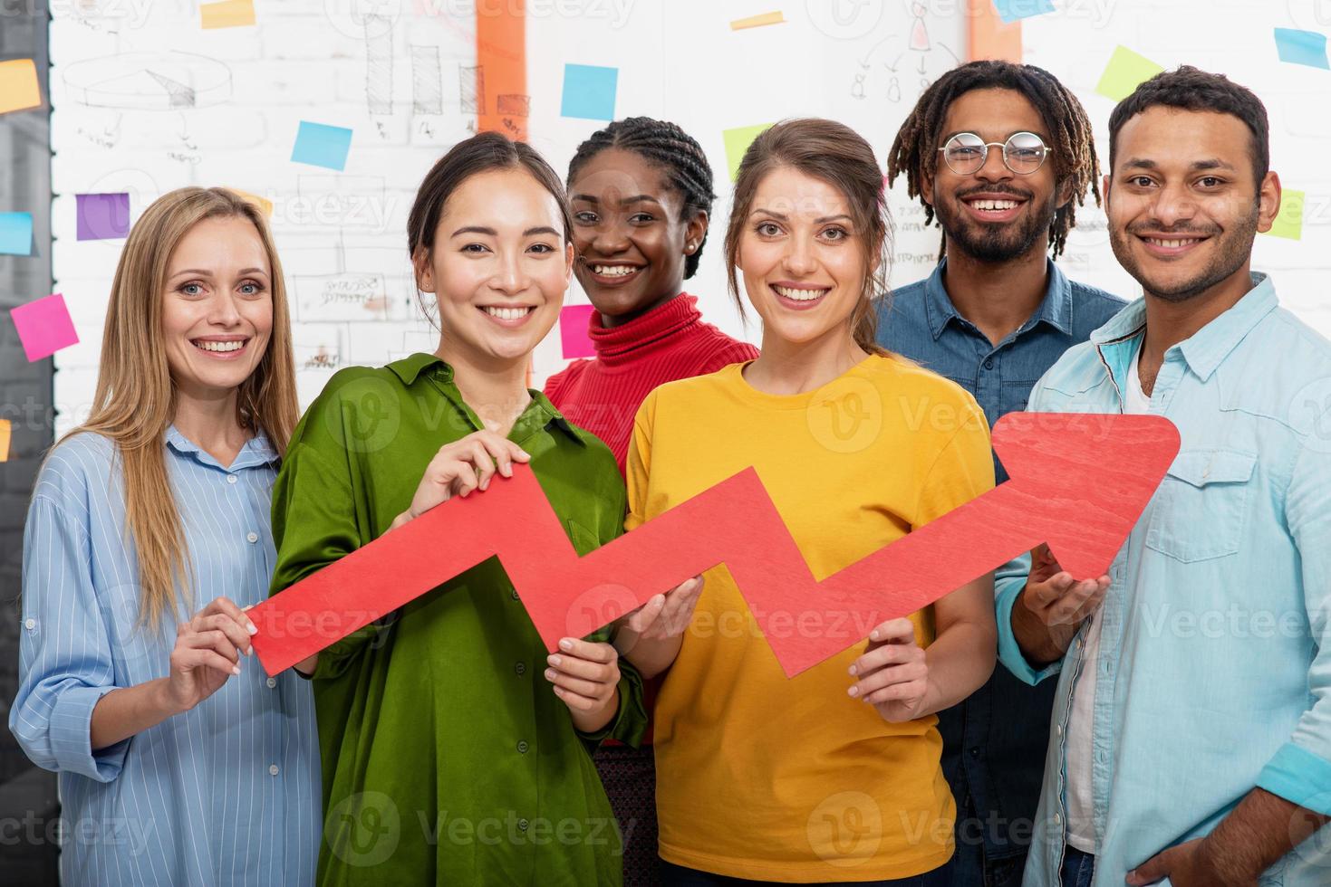ung Lycklig och färgrik företag team håll en röd statistisk pil. begrepp av växande, framgångsrik och vinst foto