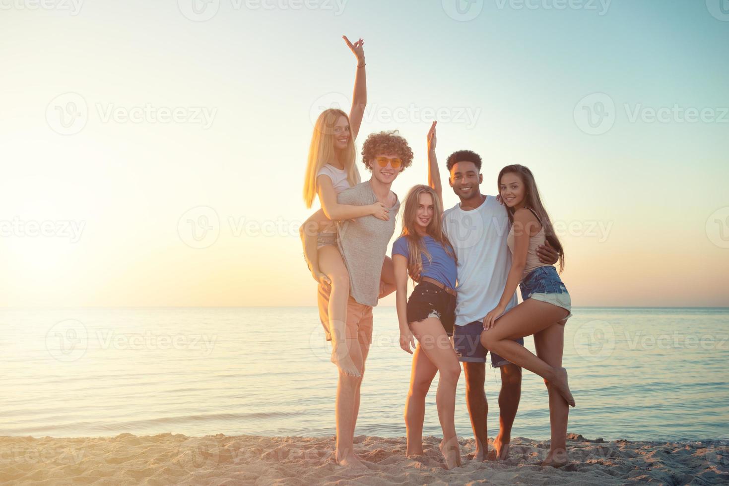 grupp av Lycklig vänner har roligt på hav strand på gryning foto