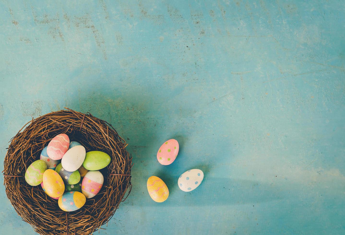 färgrik påsk ägg i bo på blå trä bakgrund med kopia Plats. foto