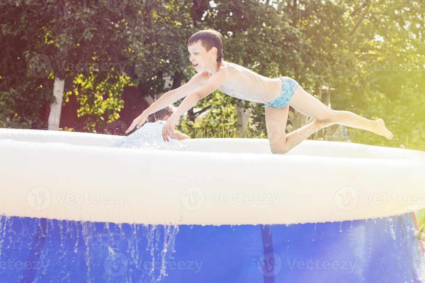 pojke Hoppar in i de simning slå samman i de trädgård på sommar foto