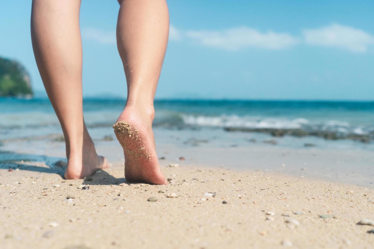 kvinnans fötter går långsamt på sandstrand foto