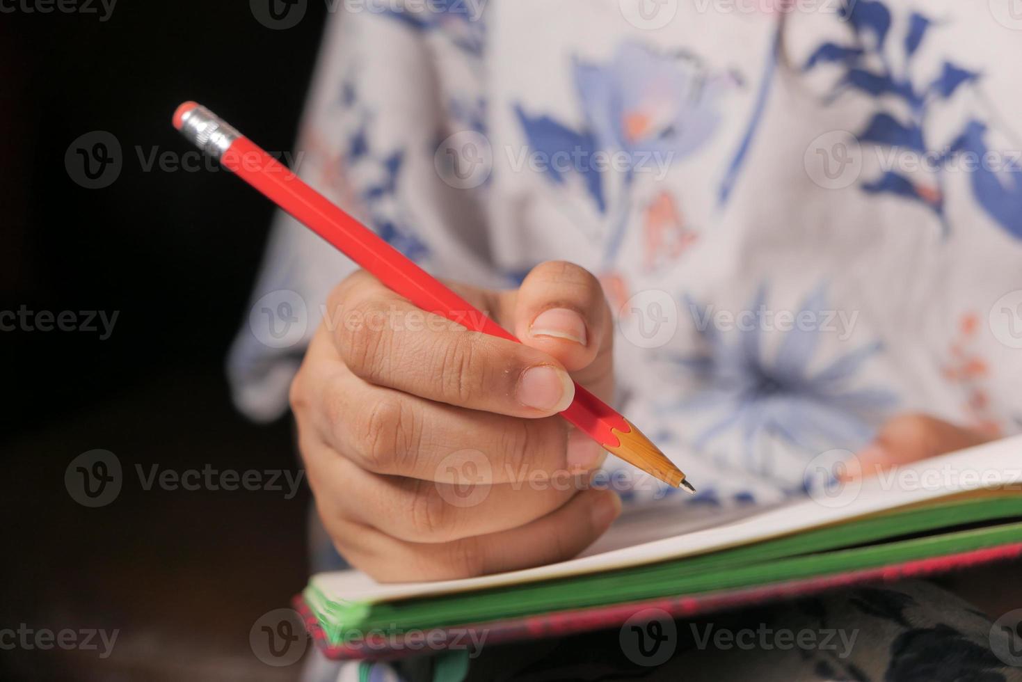 närbild på en hand som skriver med en röd penna foto