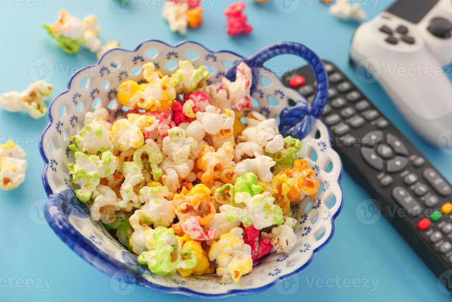närbild av färgglad popcorn och tv-fjärrkontroll på bordet foto