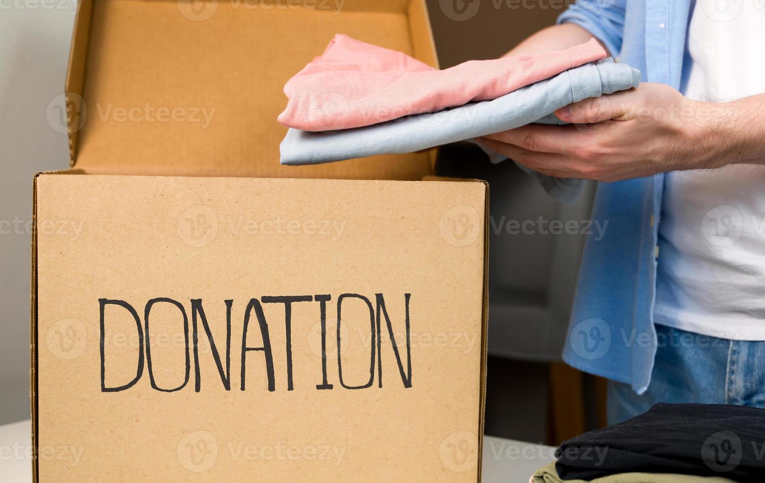 närbild av manlig händer sätta kläder i de bax. välgörenhet och donation begrepp foto