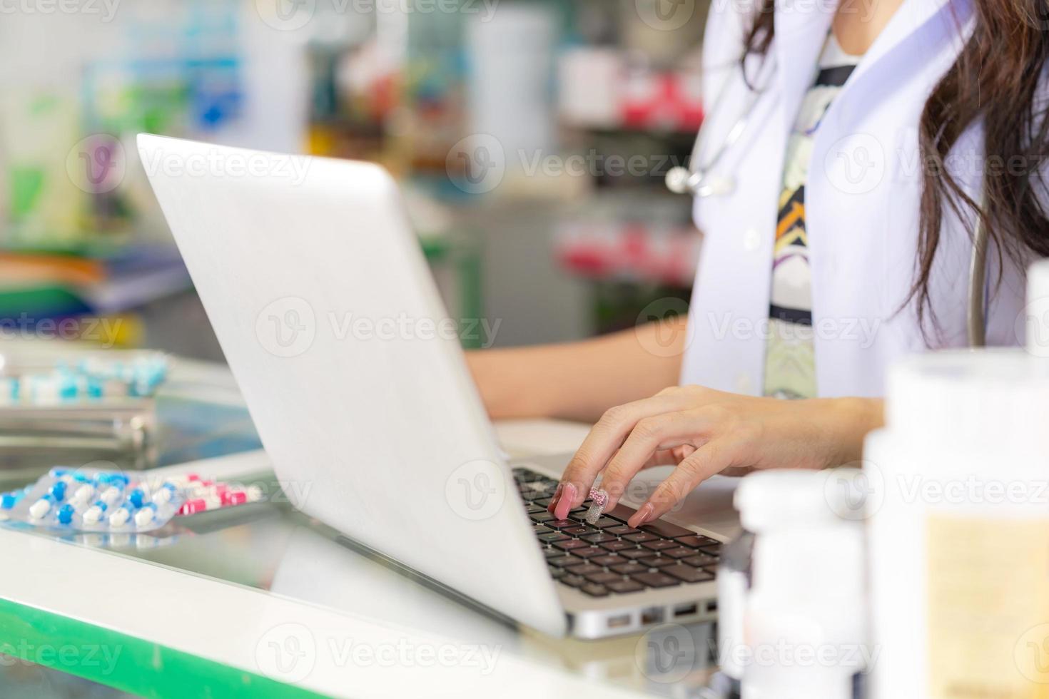 en kvinnlig apotekare som använder en bärbar dator på ett apotek foto