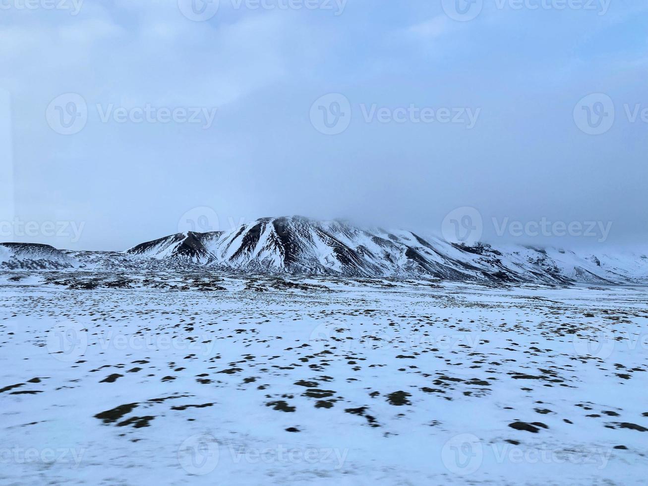 isländsk vinter- landskap med snö täckt kullar och blå molnig himmel foto