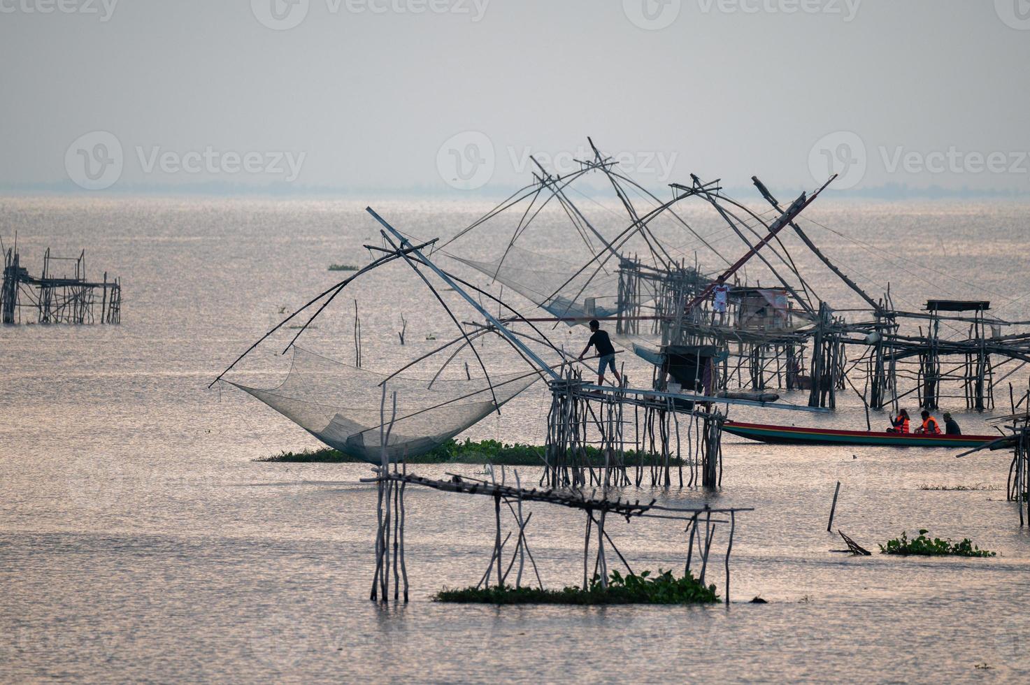 fiskare som fångar fisk med ett nät på pakpra, phatthalung, thailand foto